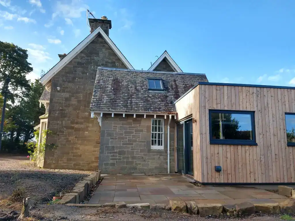 Stylish house extension with traditional stone and modern wood cladding using large windows for natural light.