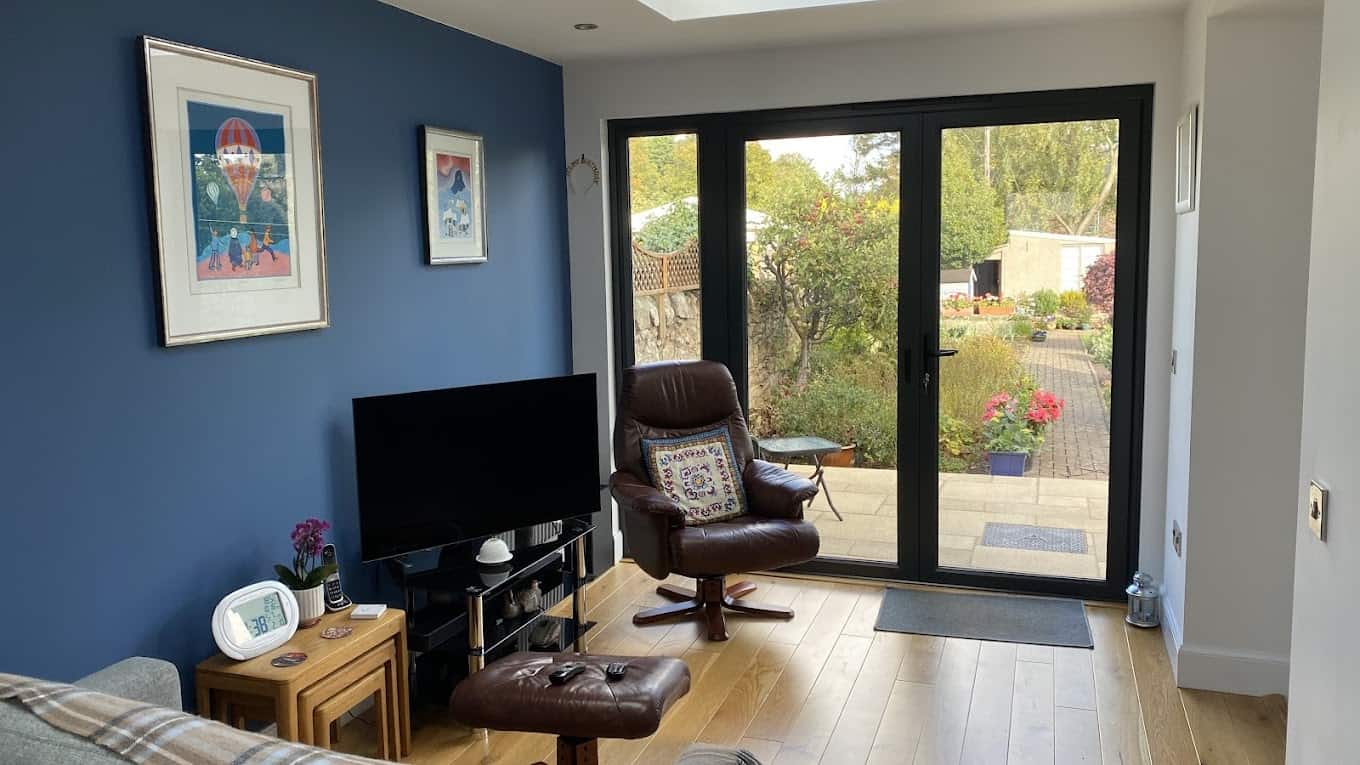 Bright living space with blue accent wall, leather armchair, and garden view, showcasing contemporary architecture.