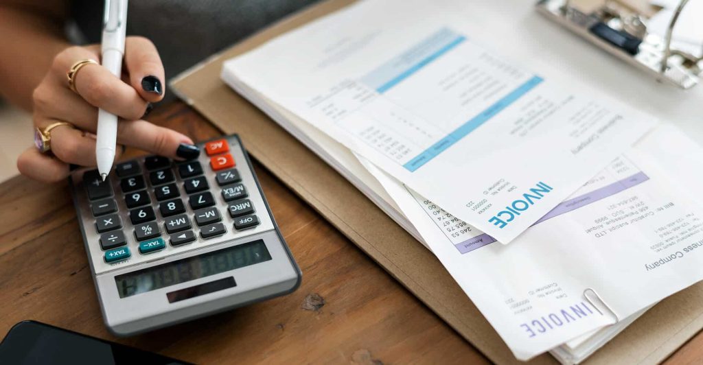 High-quality calculator, pen, and financial documents on a wooden desk, illustrating bookkeeping, accounting, and financial management concepts for ASBK website SEO.