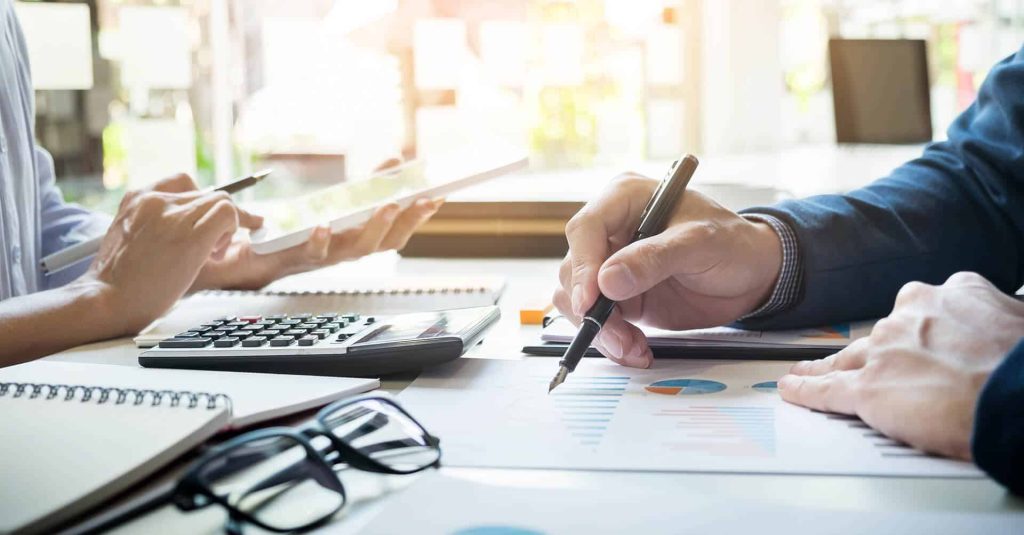 Modern business meeting with professionals analyzing data and financial reports at office desk.
