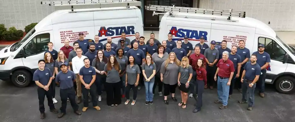 A group of employees in uniform stand in front of two company vans with "ASTAR" logos.