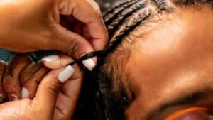 Une personne qui se fait des cornrows en coiffure protectrice pour cheveux afro