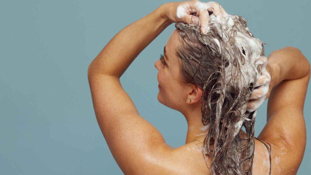 Une femme se lave les cheveux avec du shampoing après-soleil bio