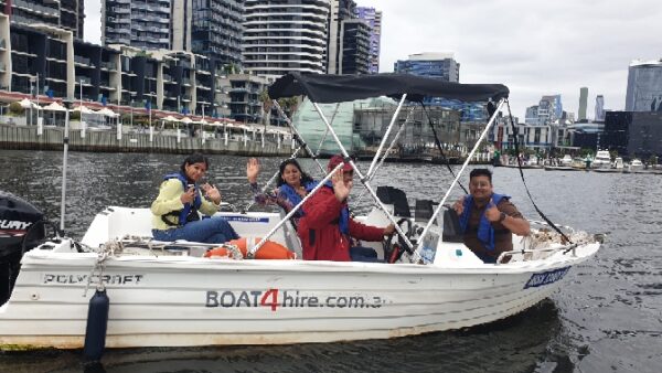 Group enjoying a boat ride on Melbourne water taxi with city skyline in background.