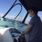 Man steering a boat at Melbourne harbor for boat rental service.