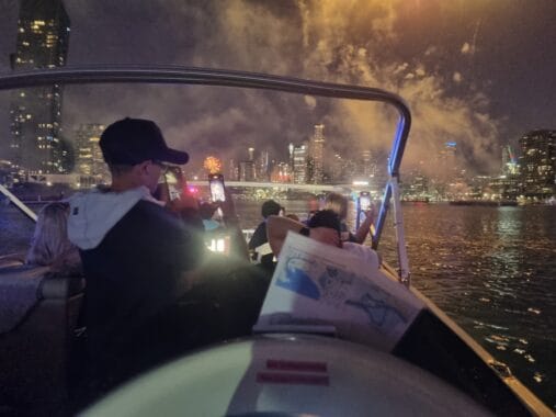 People enjoying a night boat cruise on Melbourne River with city skyline view.