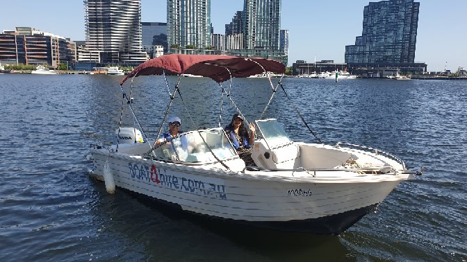 Boat4Hire Melbourne boat on water with city skyline in background.