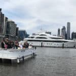 Luxury yacht in Melbourne harbor with city skyline in background.