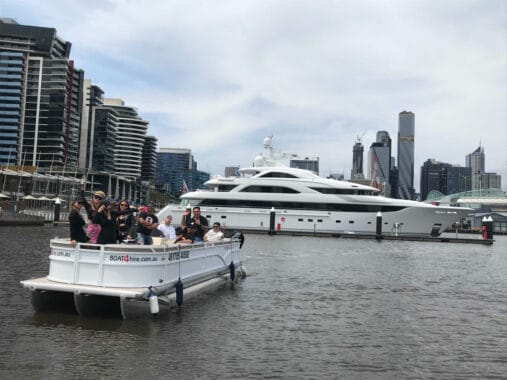 Luxury yacht in Melbourne harbor with city skyline in background.