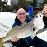Man holding a large fish on a boat in Melbourne waterway.