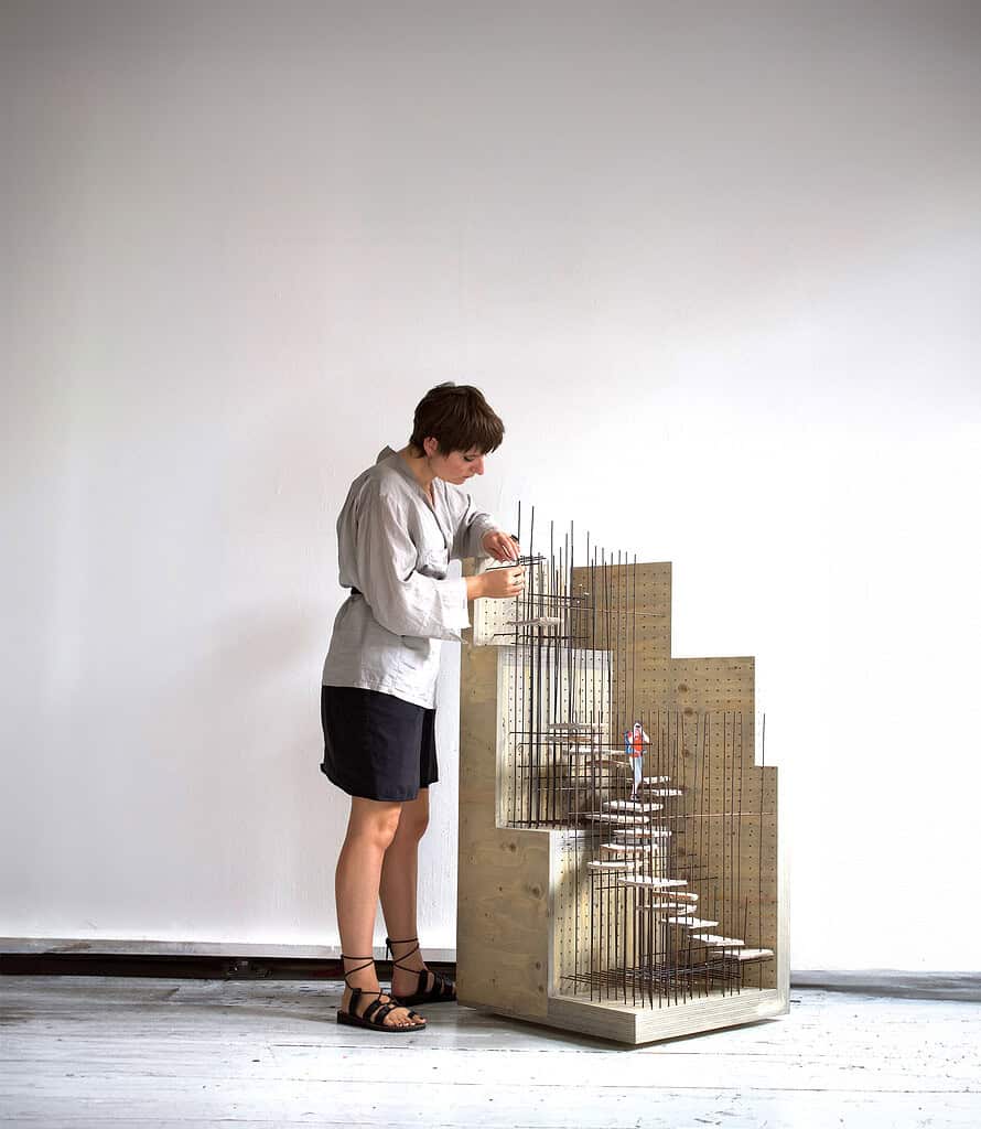Kunstnerisk boligmodel med trappe og miniaturehuse.