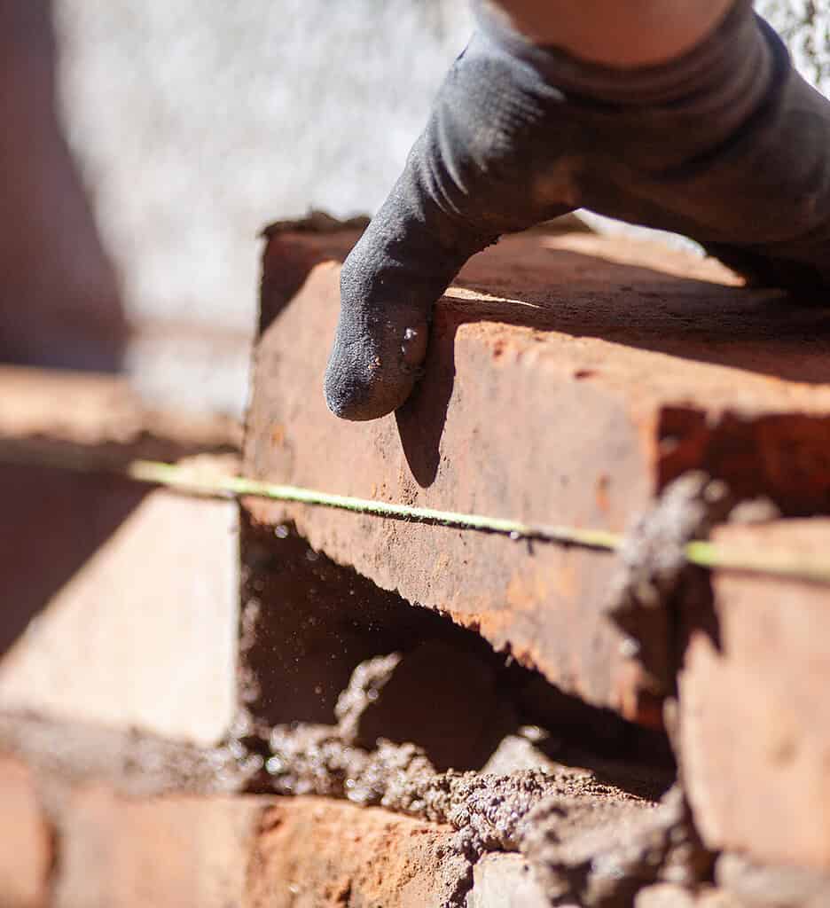 Hånd, der arbejder med træmateriale på byggepladsen.