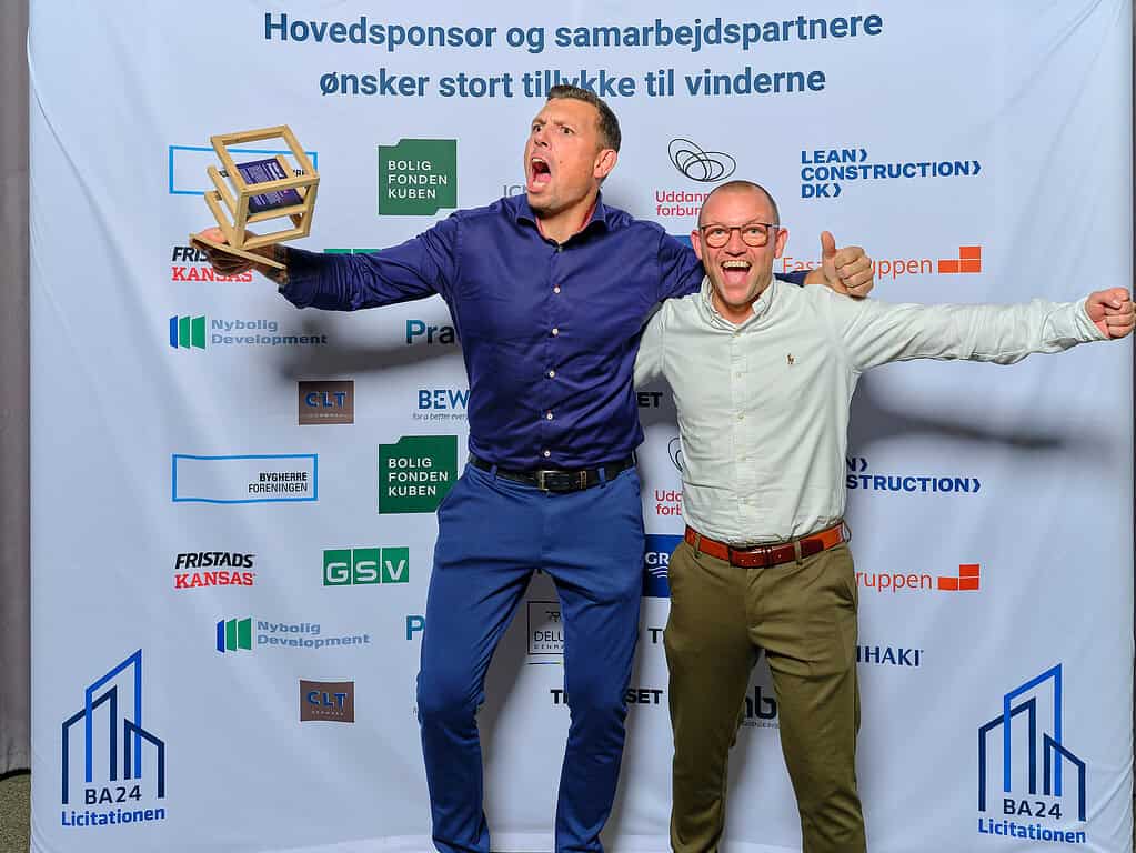 To glade mænd holder trofæ ved Byggeriets Samarbejdspris event.