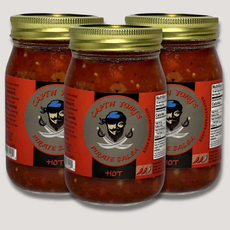 Three jars of Capt'n Tony's hot pirate salsa with gold lids, showcasing the spicy, fresh salsa produ.