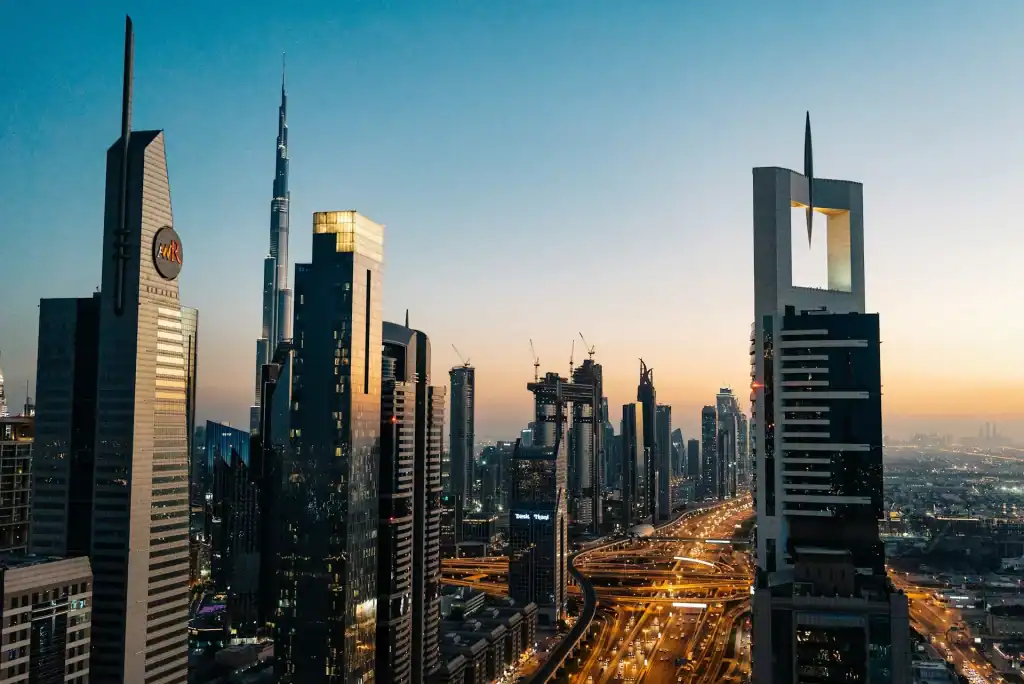 Dubai cityscape featuring tall skyscrapers and busy roads at sunset.