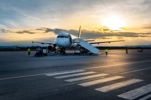 Passenger airplane on tarmac at sunset with ground crew.