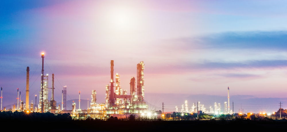 Industrial plant with chimneys and lights at sunset.