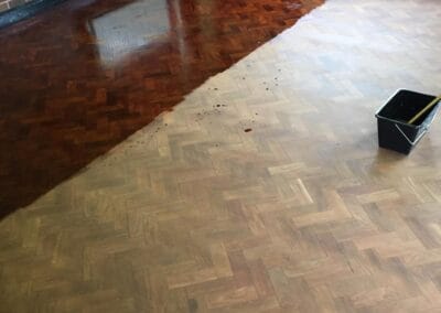 Half-treated wooden floor showcases staining process progress.