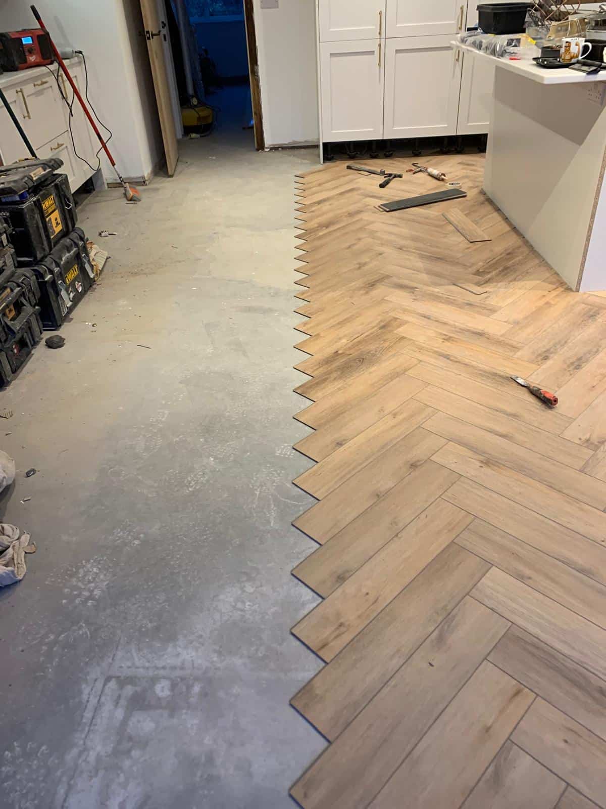 Herringbone wood flooring halfway installed in kitchen.