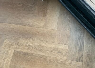 Herringbone oak flooring near glass door entrance.