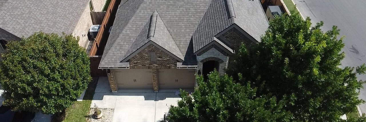 Aerial drone view of residential roof showing damage for insurance claim by Dolan Roofing & Construction in San Antonio