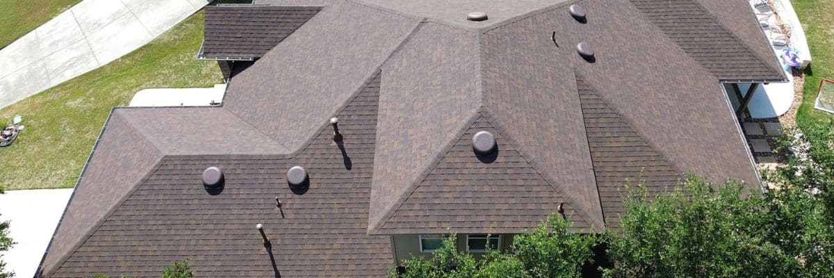 Aerial view of a house with a brown shingle roof installed by Dolan Roofing & Construction in San Antonio, TX