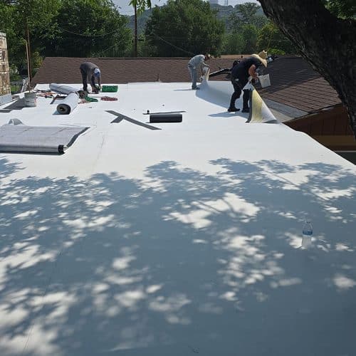 Roofing crew rolling out fleece-backed TPO membrane on a flat roof, TPO Roof Installation in Kerrville, TX by Dolan Roofing and Construction