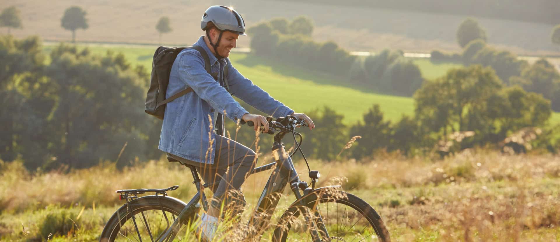 imagebild-startseite Junger Mann mit Fahrrad in ländlicher Umgebung bei Sonnenaufgang.