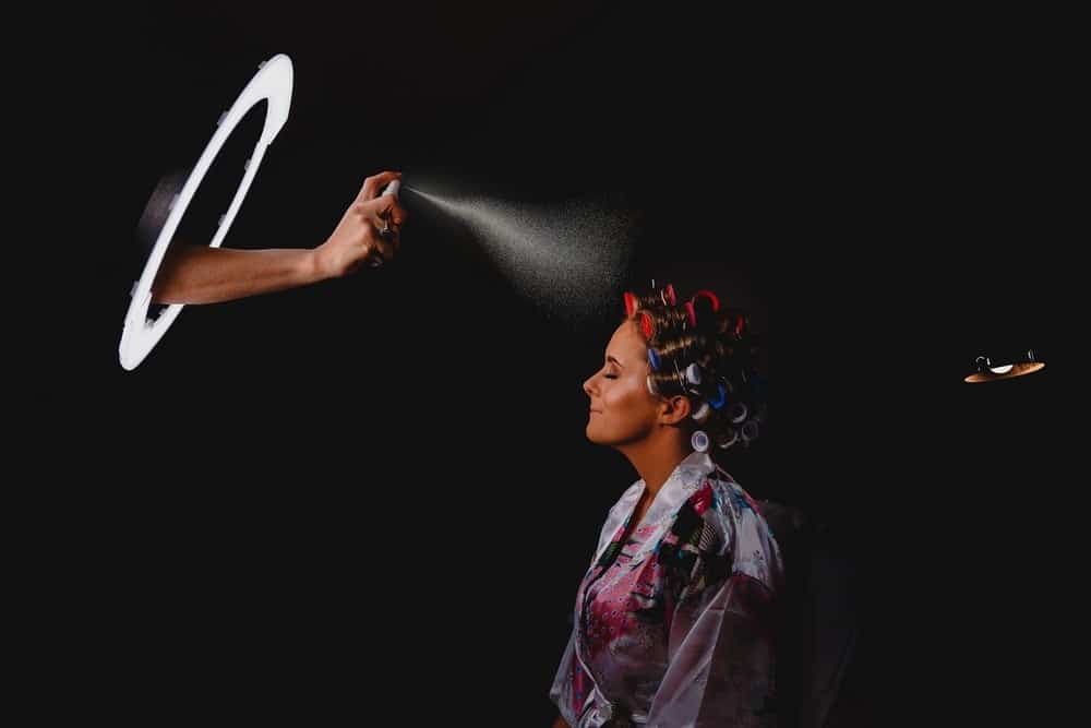 Professional wedding makeup artist preparing bride with hair rollers and setting spray at Eyecandy Weddings - Photo + Video. Expert wedding photography services in a stylish studio setting. wedding flow, tips and ideas