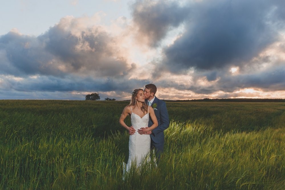 Trevenna couple embracing in green field at sunset