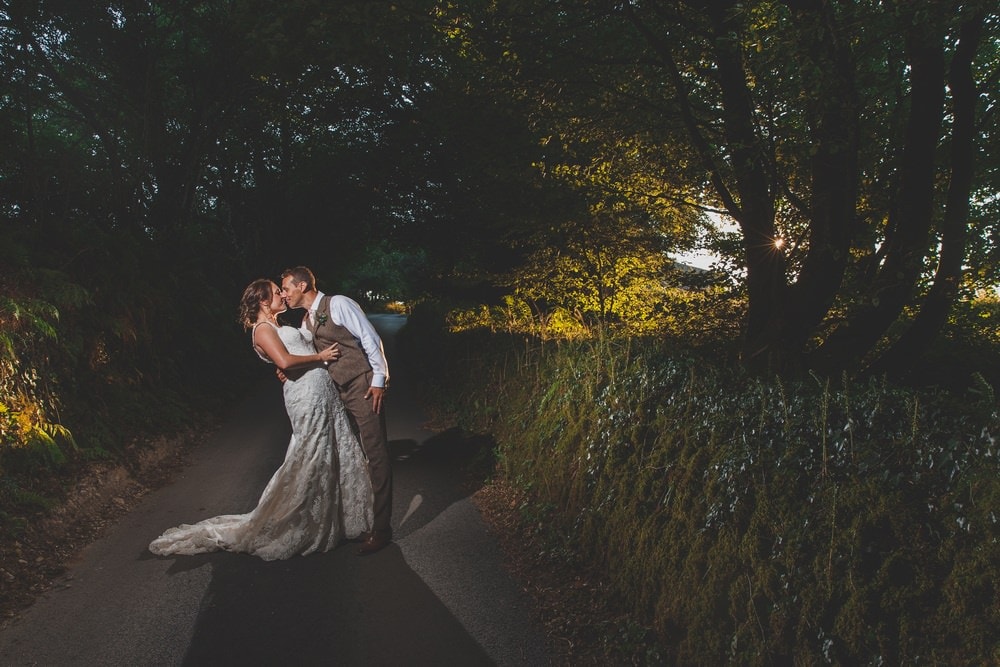 Romantic wedding couple on tree-lined country road at dusk, Trevenna Cornwall