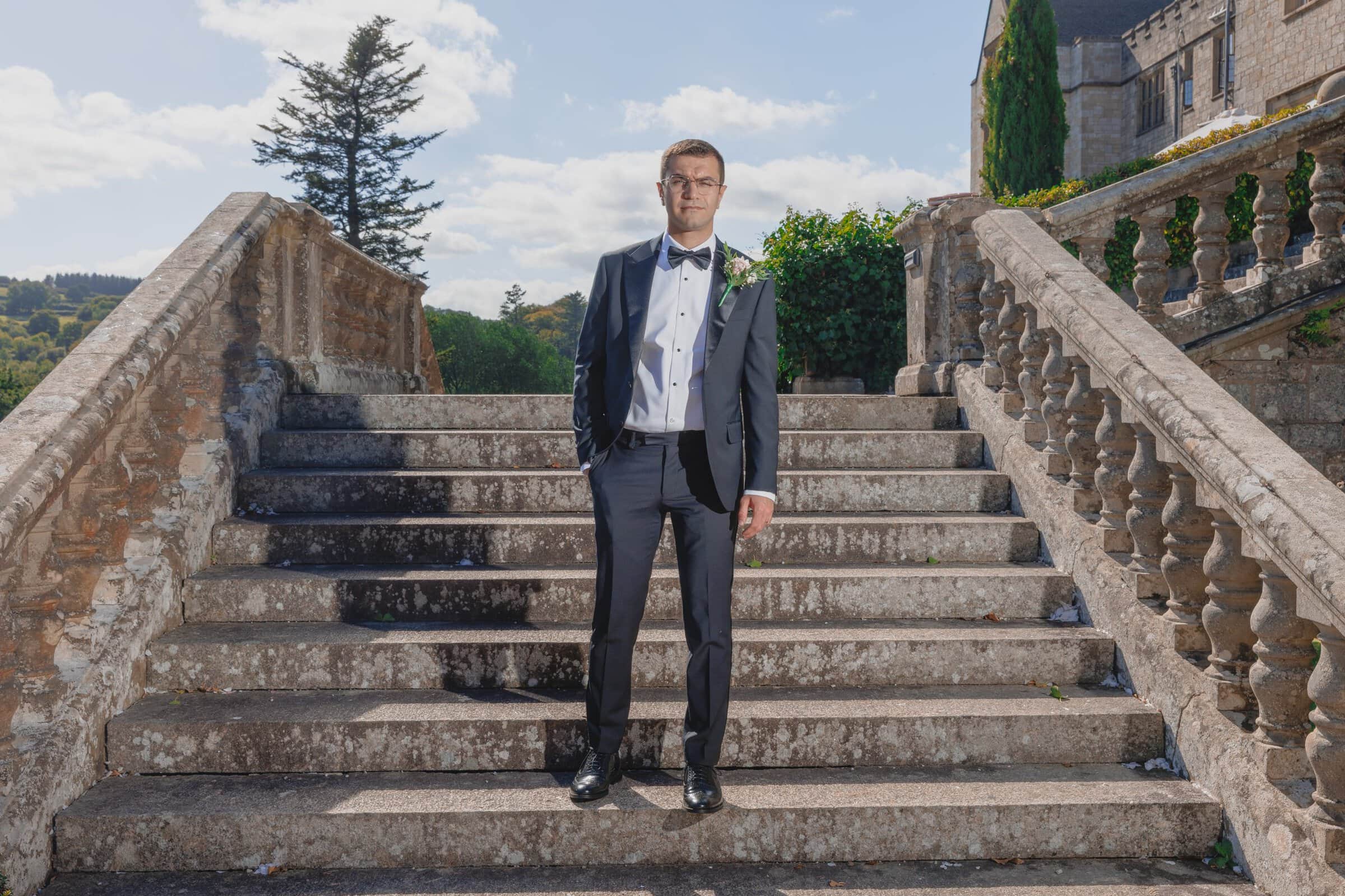 Louise + Amjad | Bovey Castle Micro Wedding, Dartmoor 22 Louise and Amjad Bovey Castle micro wedding photography — groom portrait on the stone steps