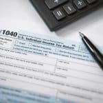 1040 U.S. Income Tax Return form with calculator and pen, representing legal and tax filing services by Farr Law Firm.