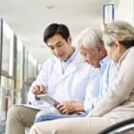 Young healthcare professional consulting elderly couple in a hospital or clinic waiting area, emphasizing elder law, healthcare law, and legal support for seniors.