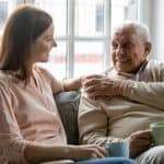 Elderly man and young woman having a heartfelt conversation at home, representing elder care and legal support for seniors.