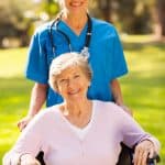 Compassionate nurse with elderly patient in wheelchair outdoors, showing healthcare and senior care services.
