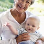 Elderly woman smiling with a baby, family care, senior support, healthy aging, legal services for seniors, Farr Law Firm.