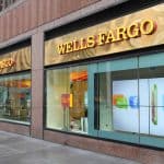 Wells Fargo bank branch exterior with large glass windows in an urban setting, featuring digital signage and inviting storefront.