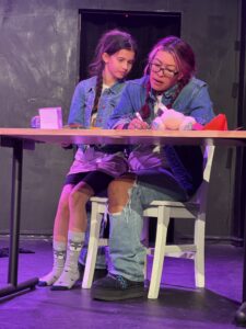 Two people performing a stage play scene.
