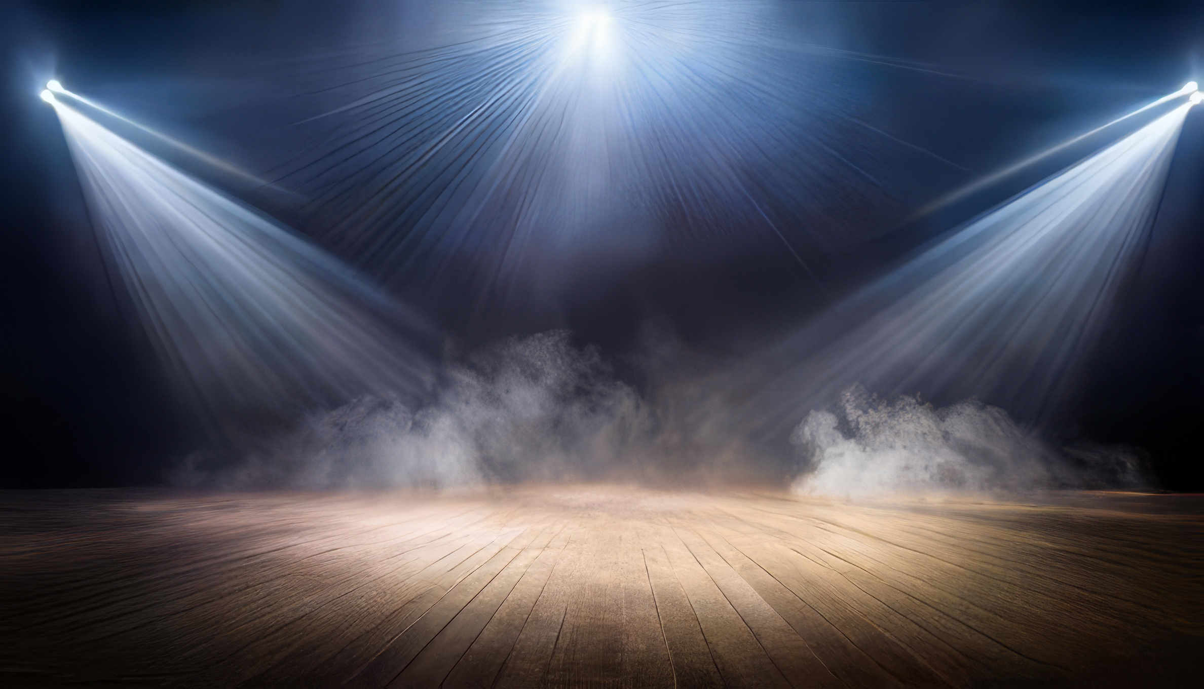 Empty stage illuminated by bright spotlights with fog effects, ready for a performance or event.