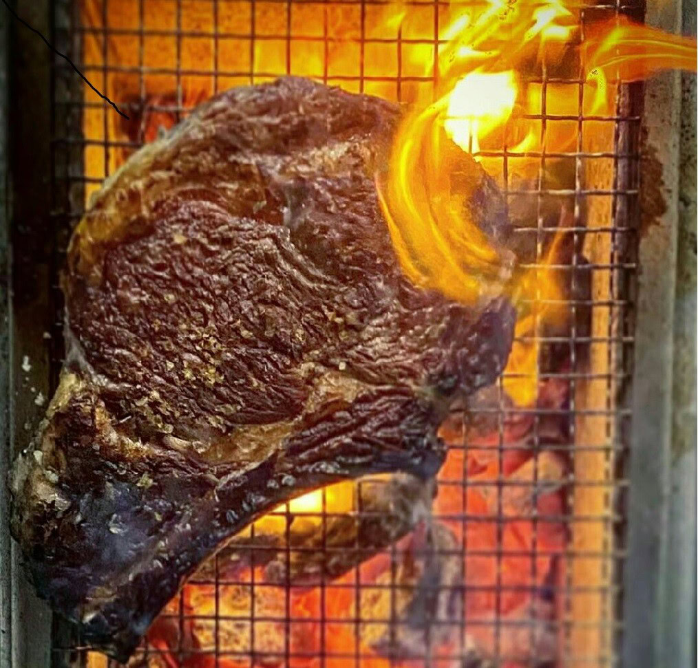 Grilled beef steak over open flame, highlighting tallow-based organic skincare ingredients.