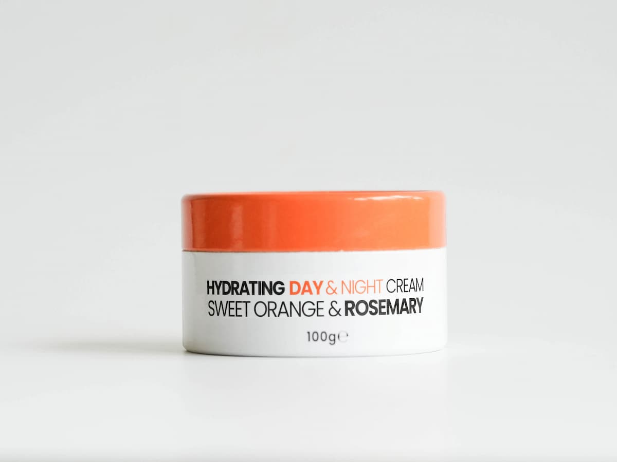 Soft orange and white jar of tallow skincare cream with organic ingredients for hydration.