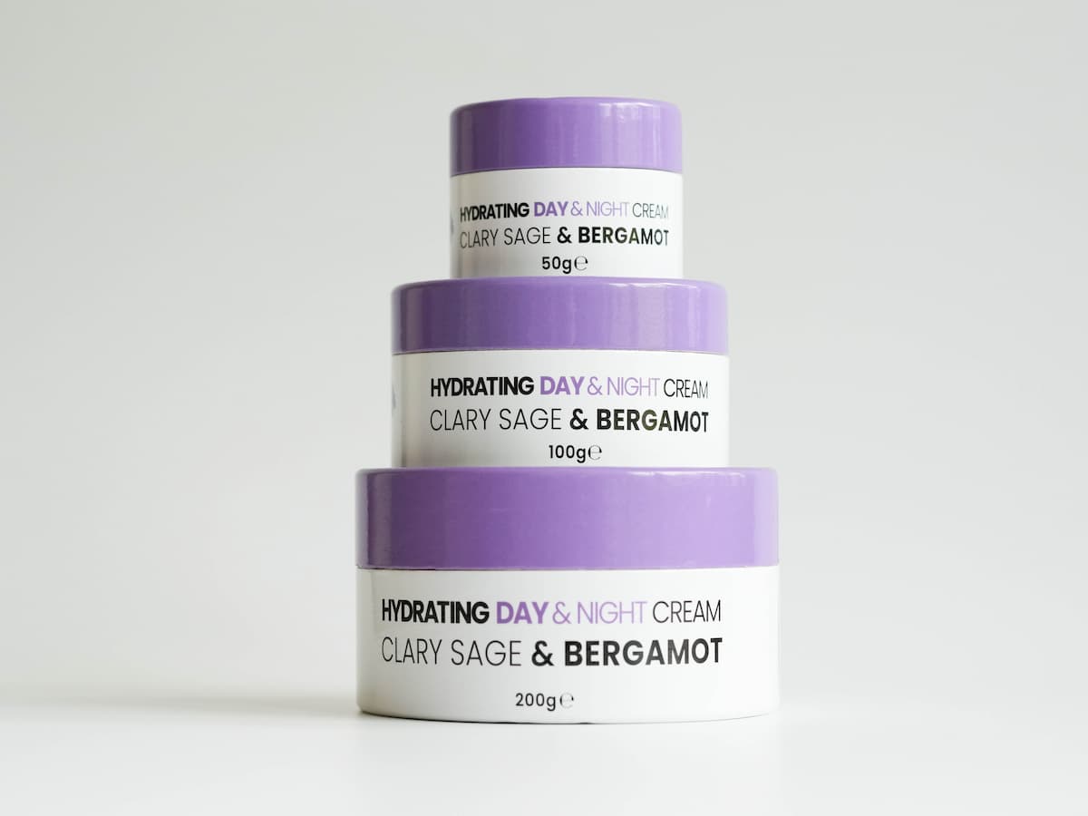 Soft lavender jars of tallow skincare cream stacked, emphasizing organic ingredients and hydration b.