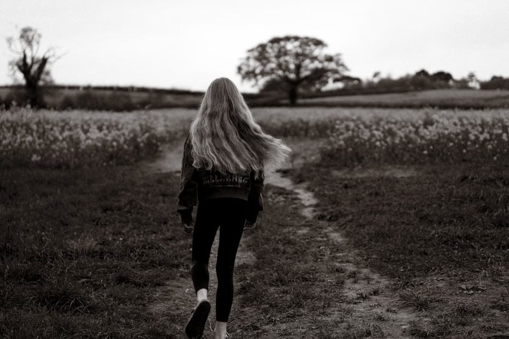 Soft-skinned woman walking outdoors in a natural landscape, promoting organic tallow skincare produc.