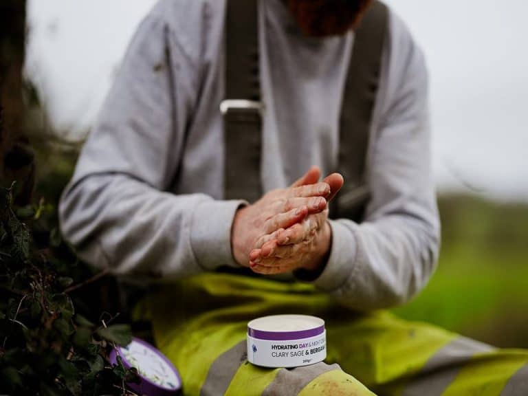 Person applying organic tallow skincare outdoors for protection.