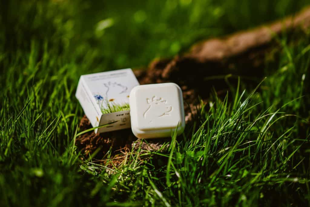 Organic tallow skincare soap on grass with natural packaging.