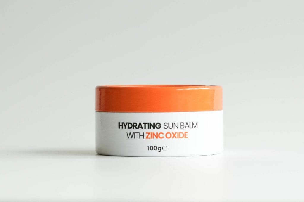 White and orange Hayes Meadow Hydrating Sun Balm jar with clear product label visible.