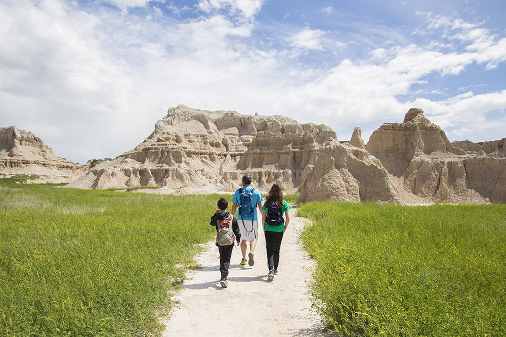 2025 U.S. National Park list by State (Free Printable Map & Checklist) View of hiking trail with Badlands formations in the distance.