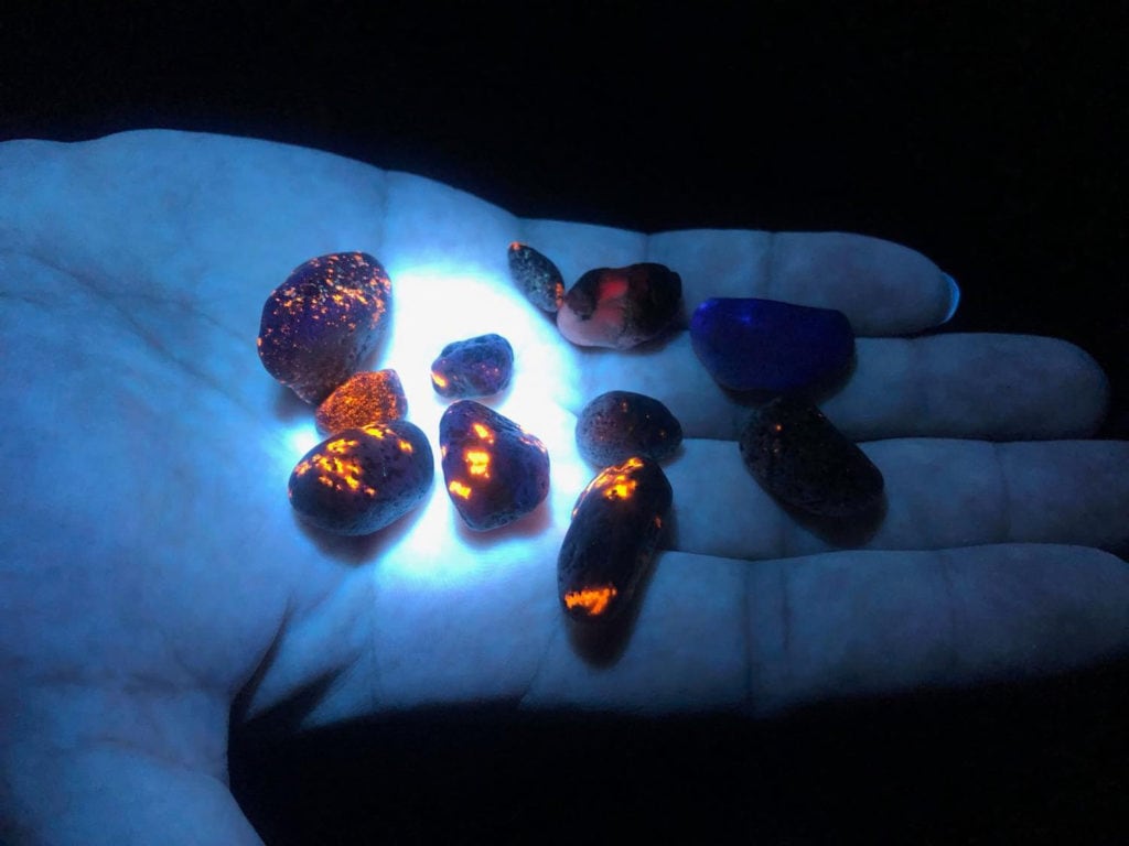 Yooperlite Rocks – Guide to Michigan’s Glowing Rocks Close-up of a Yooperlite rock glowing orange under UV flashlight at night