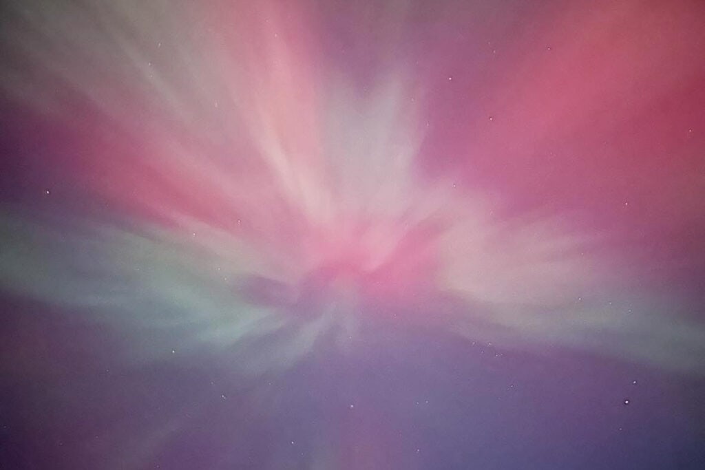 Where to See Northern Lights in Michigan: Upper & Lower Peninsula Northern lights showing off a vibrant display of pink, purple, green and white